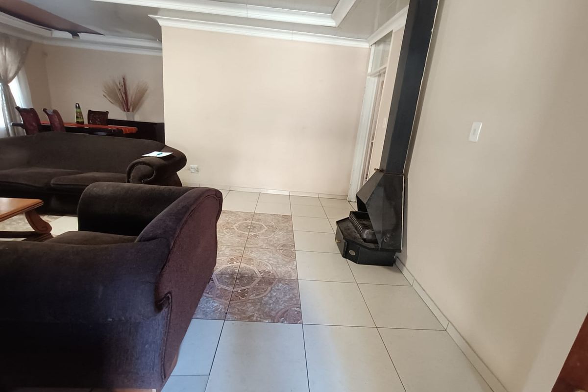 A living area featuring a built-in metal fireplace and tiled flooring, providing a functional space with potential for modern updates.