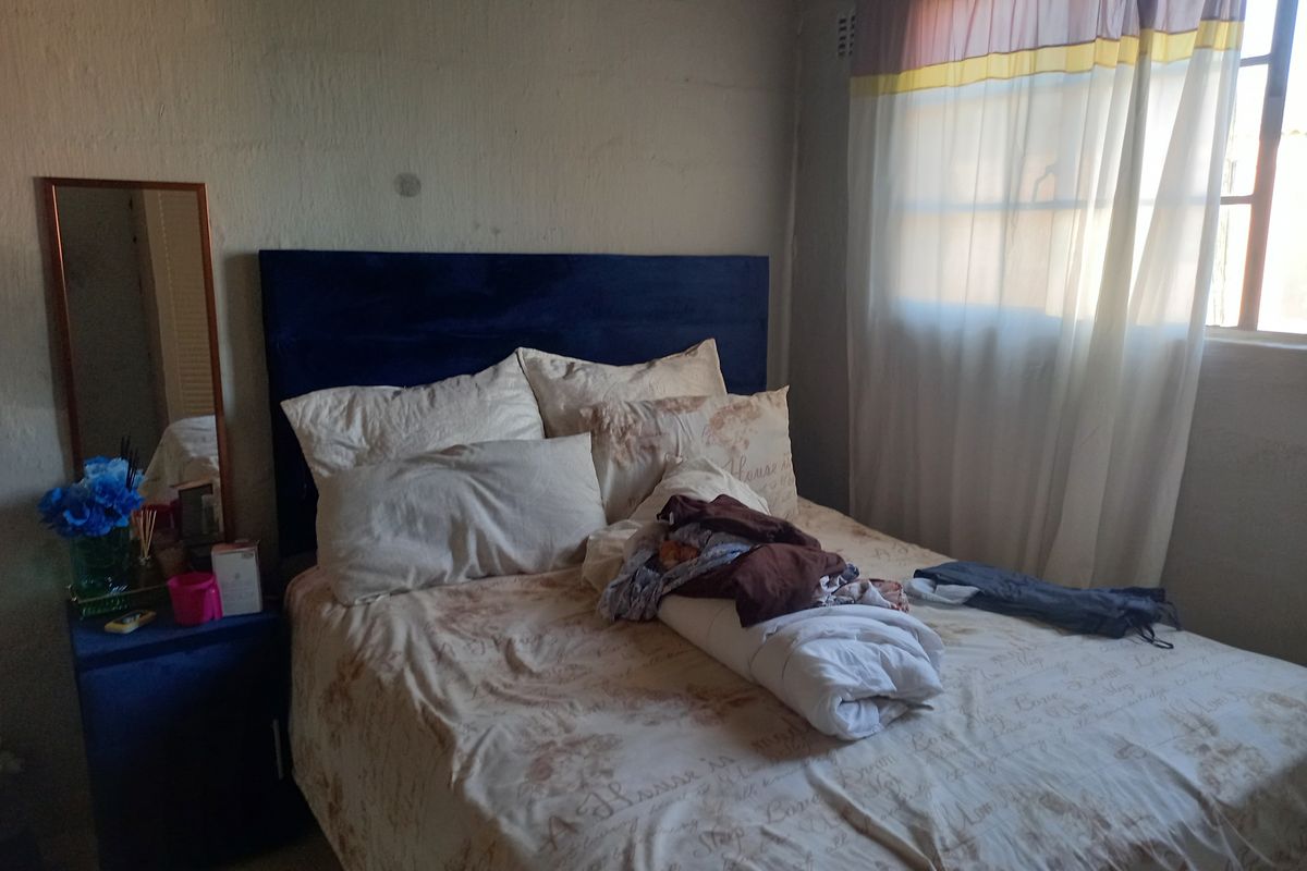 A bedroom featuring a window with curtains and a textured wall finish.