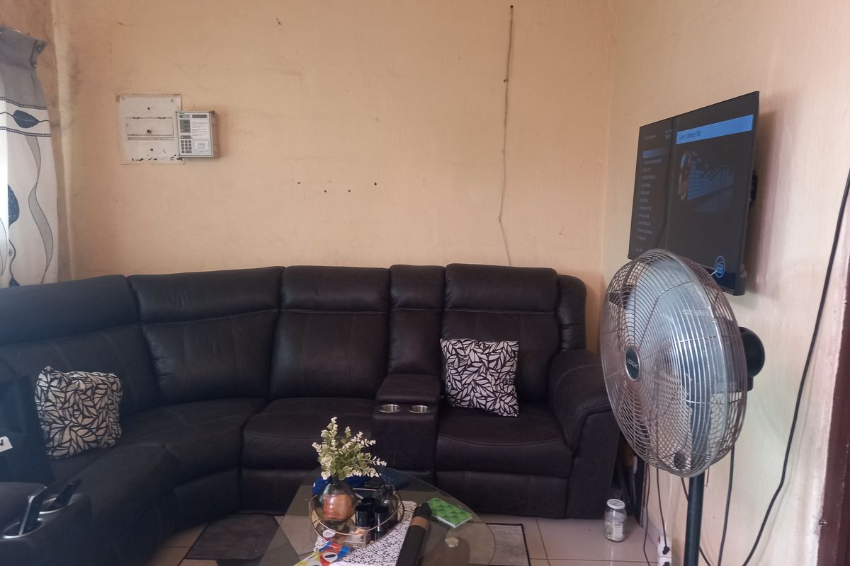 A living room featuring tiled flooring and wall-mounted television, requiring cosmetic updates to the wall finishes and electrical management.