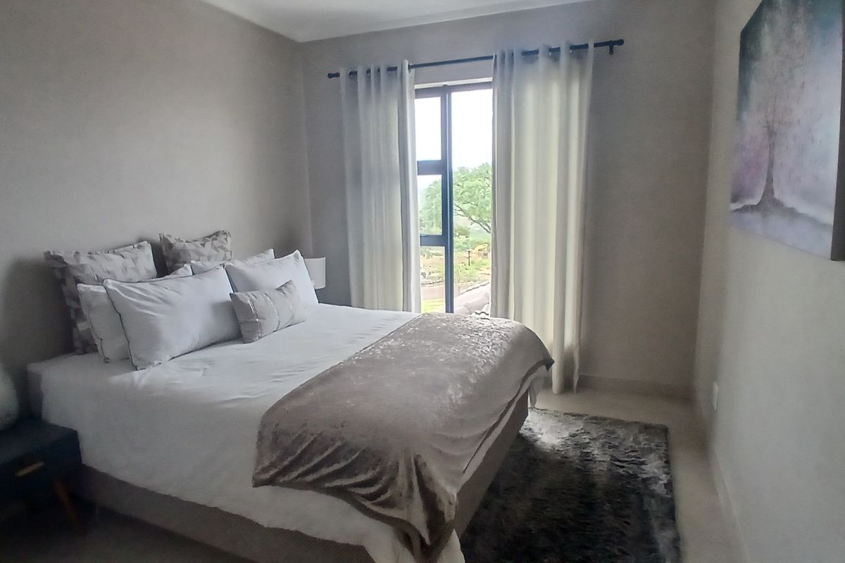 A well-maintained bedroom featuring neutral wall tones, tiled flooring, and a large window with natural light.