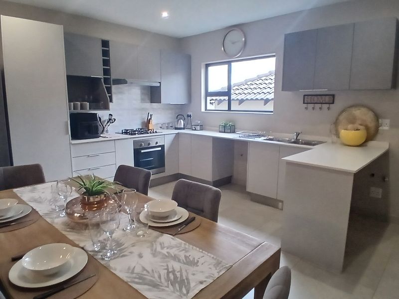 Modern open-plan kitchen featuring sleek cabinetry, stone countertops, integrated appliances, and a seamless flow into the dining area.