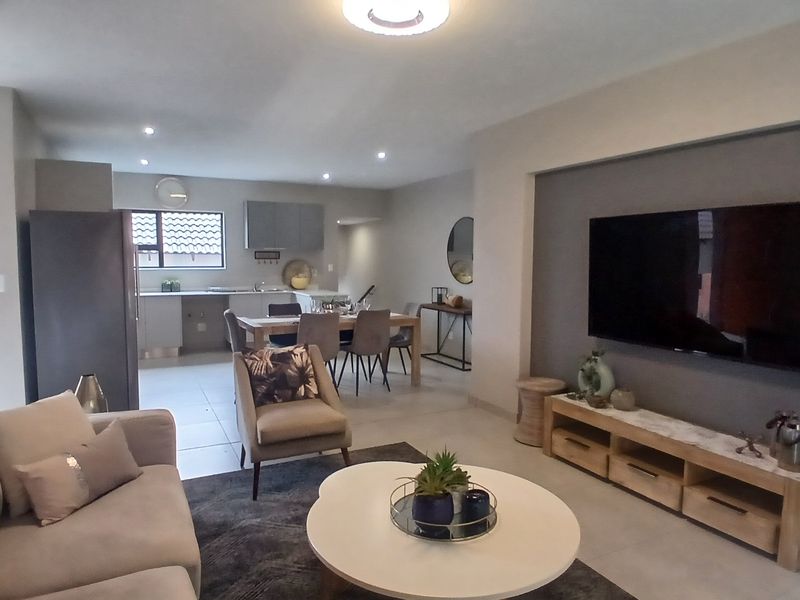 Spacious open-plan living and dining area featuring modern tiled flooring, recessed lighting, and a seamless flow into a functional kitchen space.