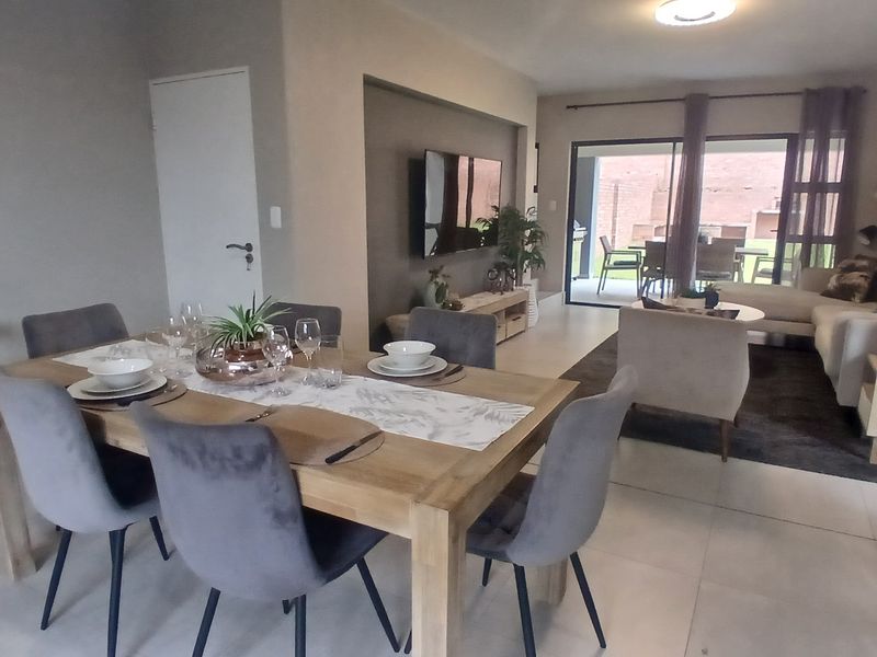 Spacious open-plan living and dining area featuring tiled floors, a recessed wall niche for media, and large sliding doors leading to the patio.