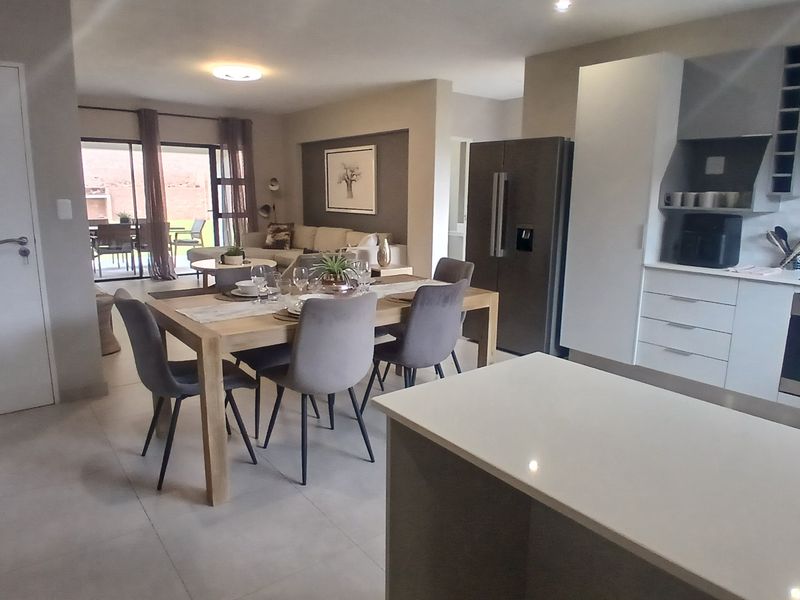 Spacious open-plan living area featuring a modern kitchen with stone countertops, built-in appliances, and seamless flow to the outdoor patio.