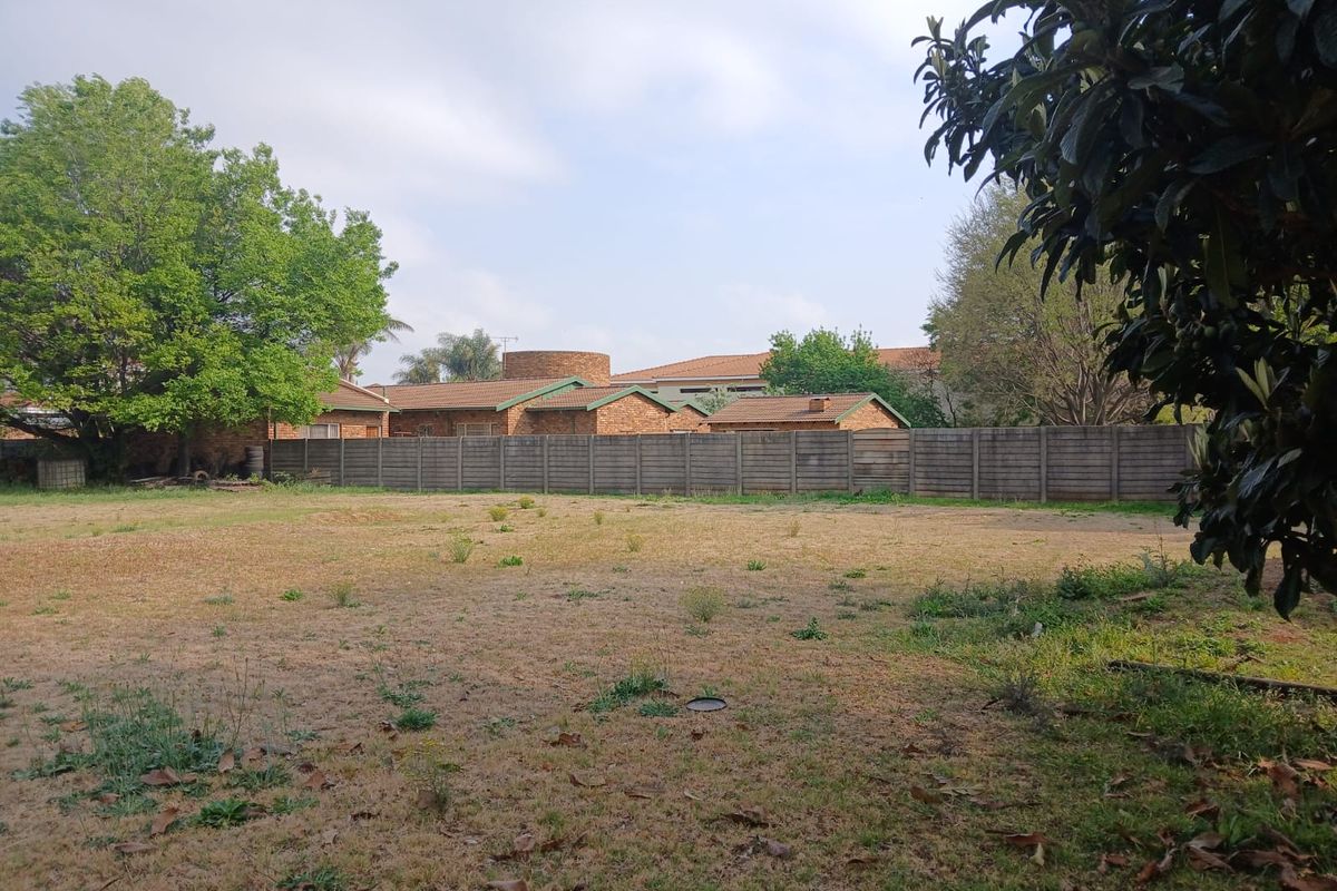 A view of a vacant residential plot featuring a level grassed area enclosed by a precast concrete boundary wall.