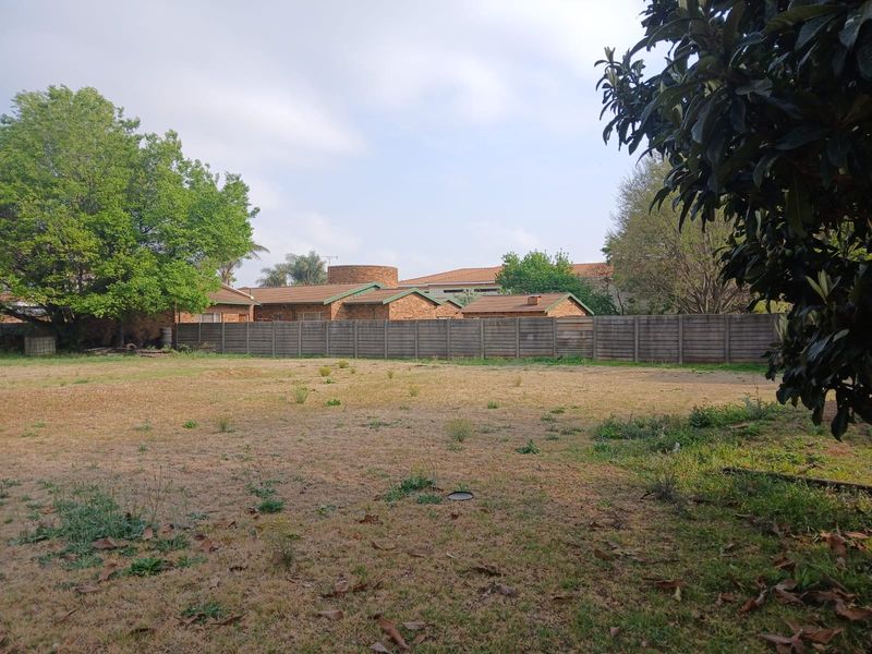A view of a vacant residential plot featuring a level grassed area enclosed by a precast concrete boundary wall.