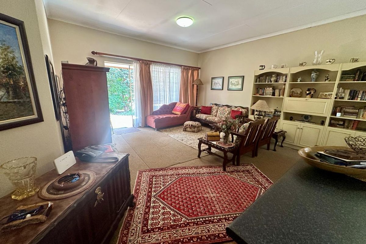 A spacious living room featuring neutral walls, carpeted flooring, and large sliding glass doors providing direct access to the outdoor patio area.