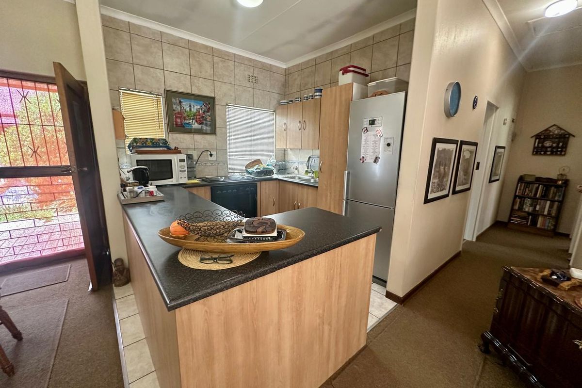 Compact kitchen featuring laminate cabinetry, dark countertops, tiled splashbacks, and direct access to an exterior door.