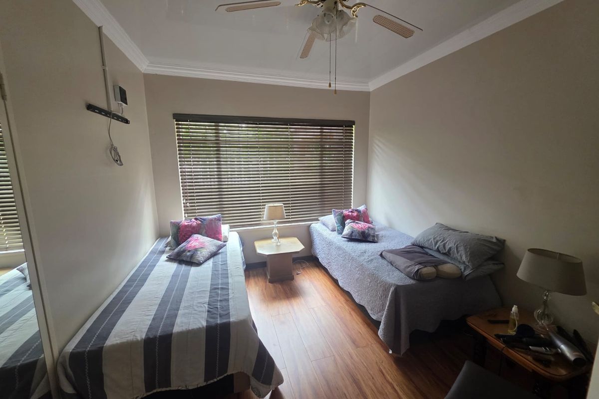 A functional bedroom featuring wood-look flooring, a ceiling fan, and window blinds, providing a comfortable space for rest.