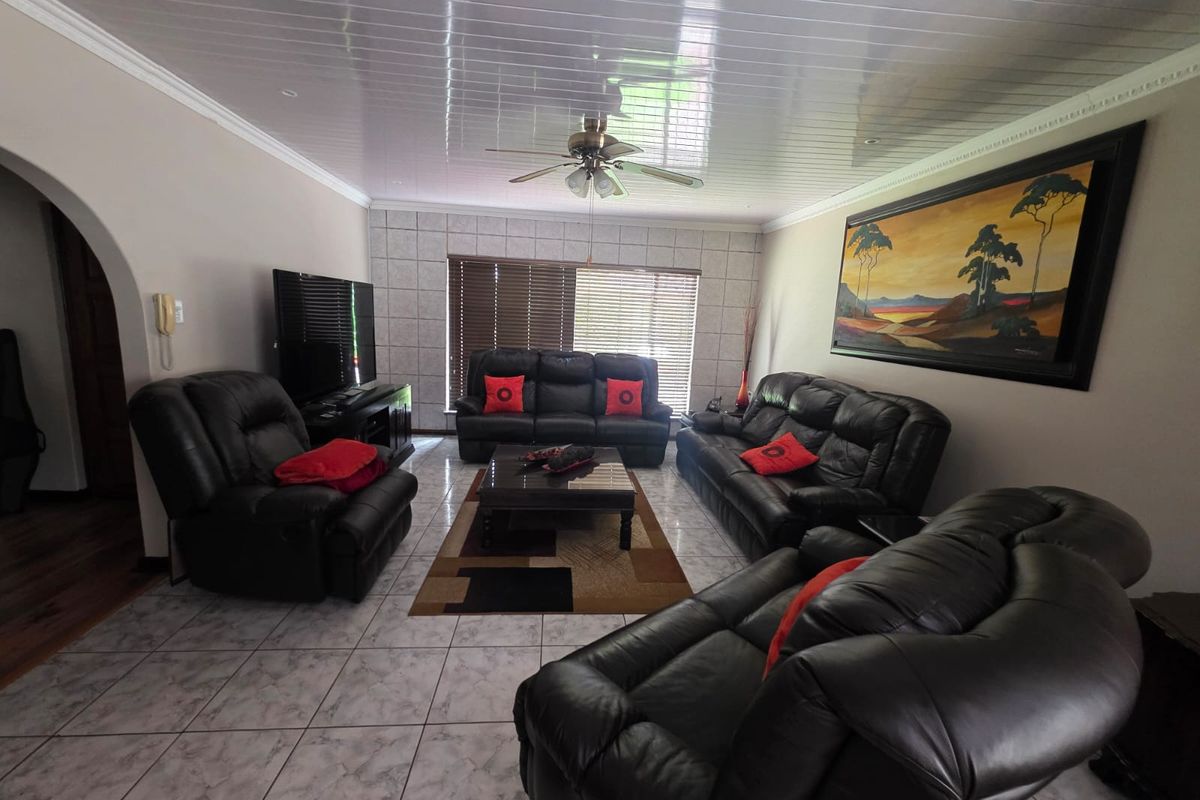 Spacious living room featuring tiled flooring, a ceiling fan, and a tiled feature wall surrounding the window area.