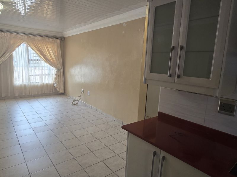 Open plan living and kitchen area featuring tiled flooring, built-in cabinetry with red countertops, and a PVC ceiling finish.