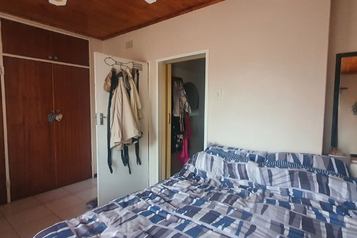 A bedroom featuring built-in wooden cupboards, tiled flooring, and a timber-paneled ceiling, offering a functional and traditional layout.