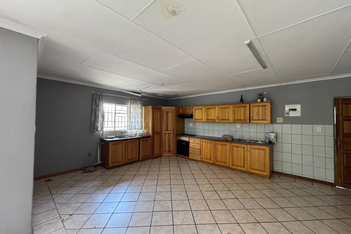 Spacious kitchen featuring wooden cabinetry, built-in oven, and tiled flooring. The area requires cosmetic updates and ceiling repairs to reach its full potential.