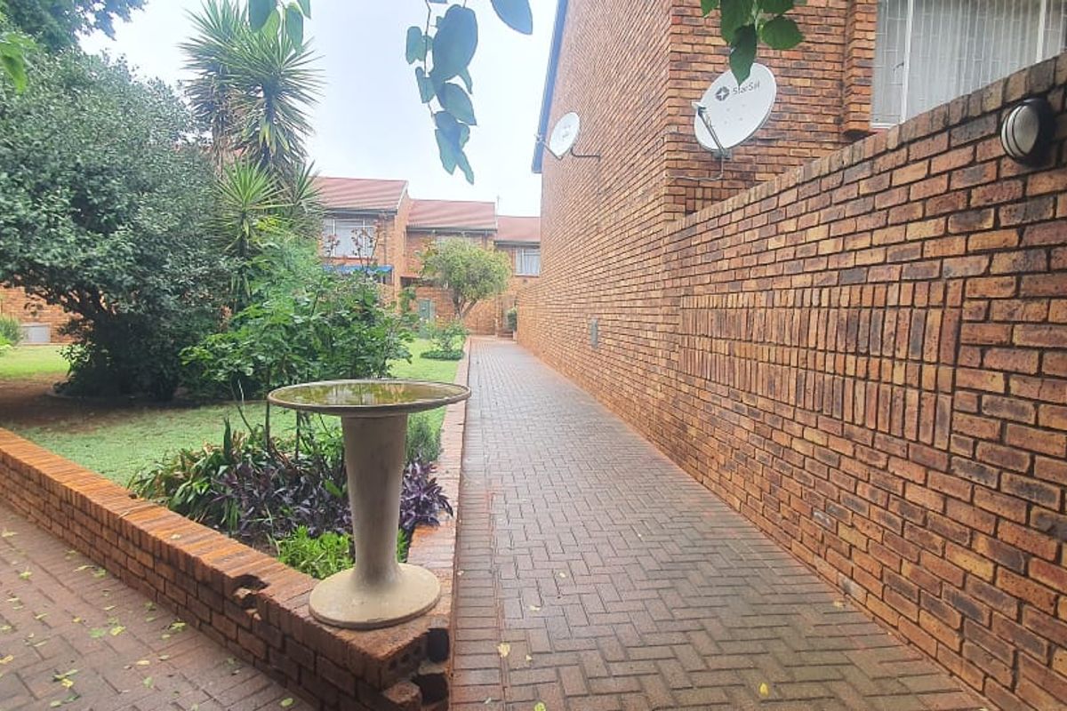 A side walkway featuring brick paving, a low brick retaining wall, and access to a landscaped garden area.
