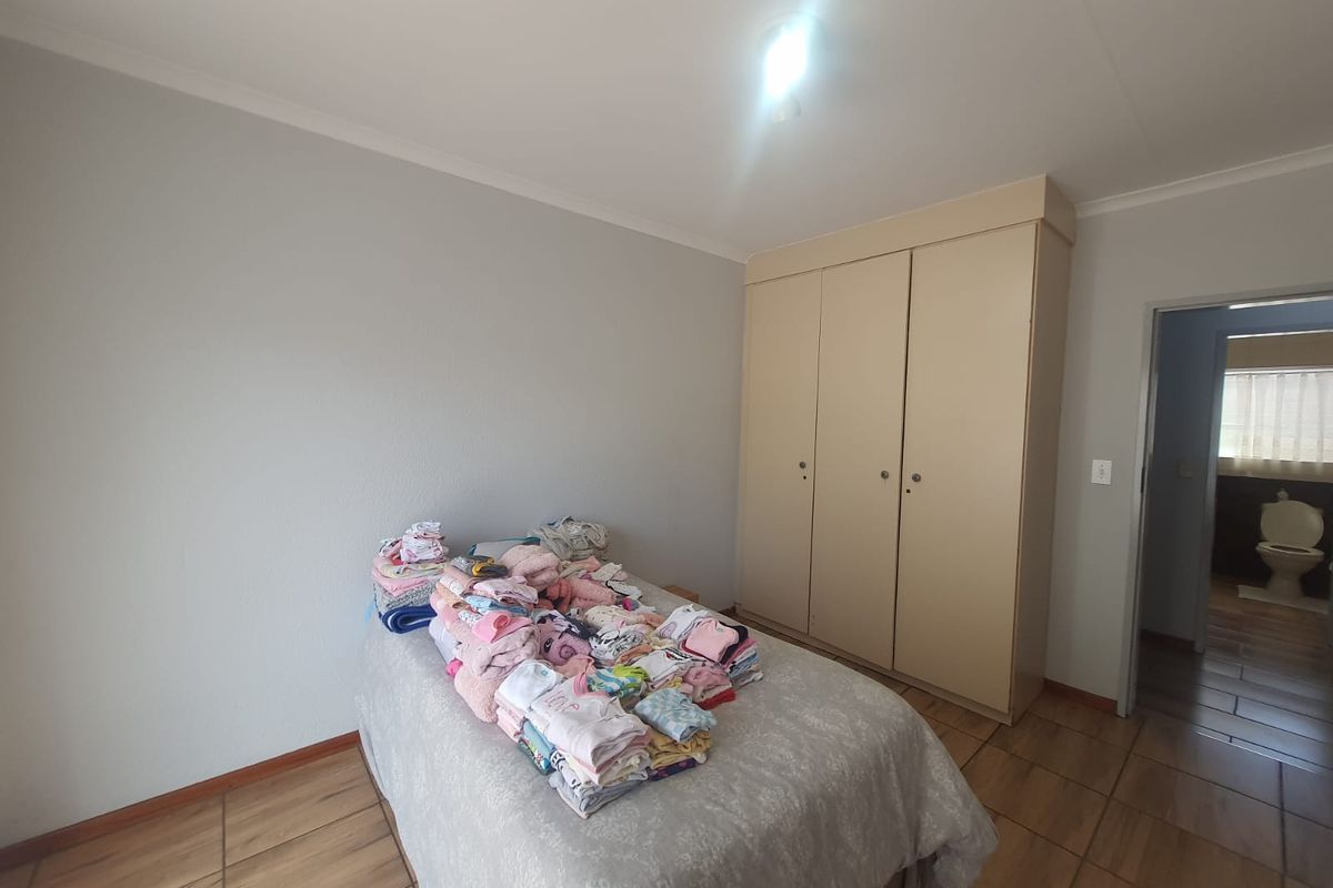 A bedroom featuring built-in cupboards, tiled flooring, and an adjoining en-suite bathroom.