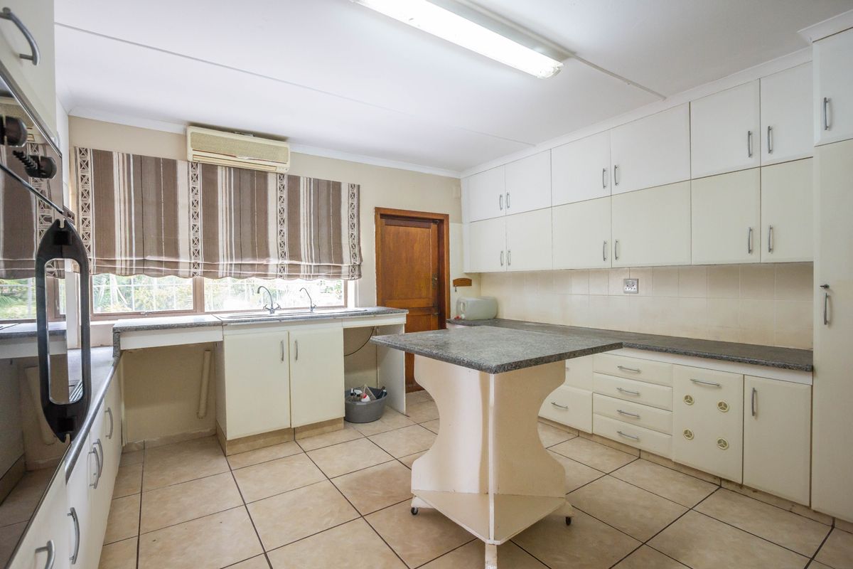 A functional kitchen featuring white cabinetry, stone-look countertops, a central island, and tiled flooring, offering a practical layout for daily meal preparation.