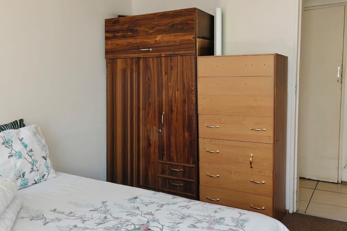 A bedroom featuring neutral walls, a timber-paneled ceiling, and carpeted flooring, providing a functional and simple living space.
