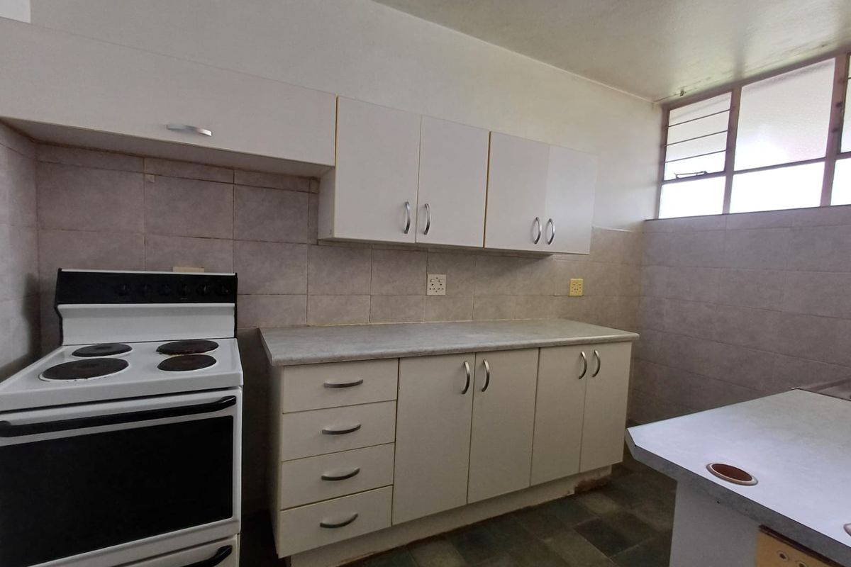 Functional kitchen featuring white cabinetry, tiled splashbacks, and a freestanding electric stove, offering a practical layout for daily meal preparation.