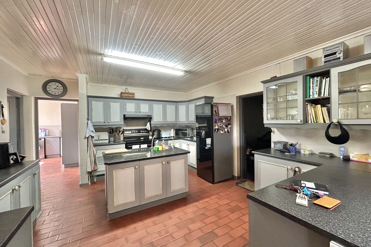 Spacious kitchen featuring a central island, ample cabinetry, and tiled flooring, offering a functional layout with direct access to adjacent utility areas.