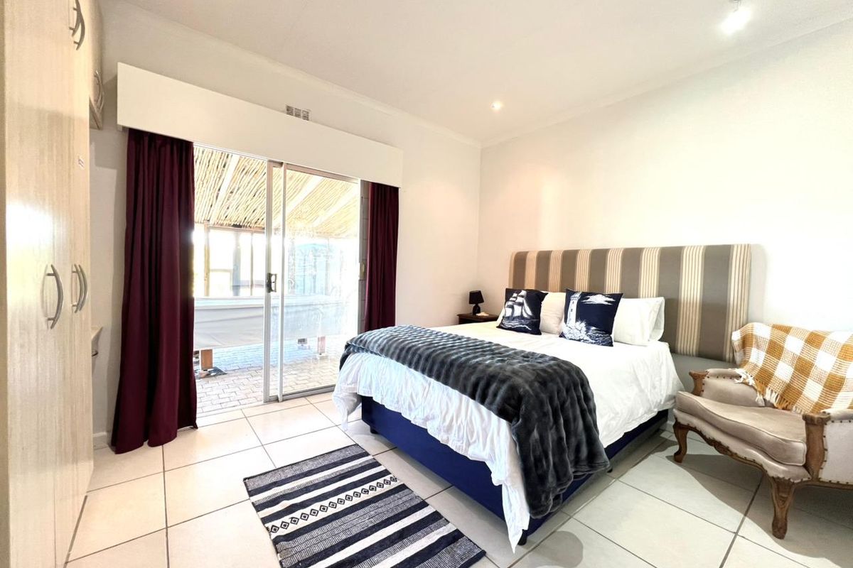 A bright bedroom featuring tiled flooring, built-in cupboards, and sliding glass doors that provide direct access to an outdoor patio area.