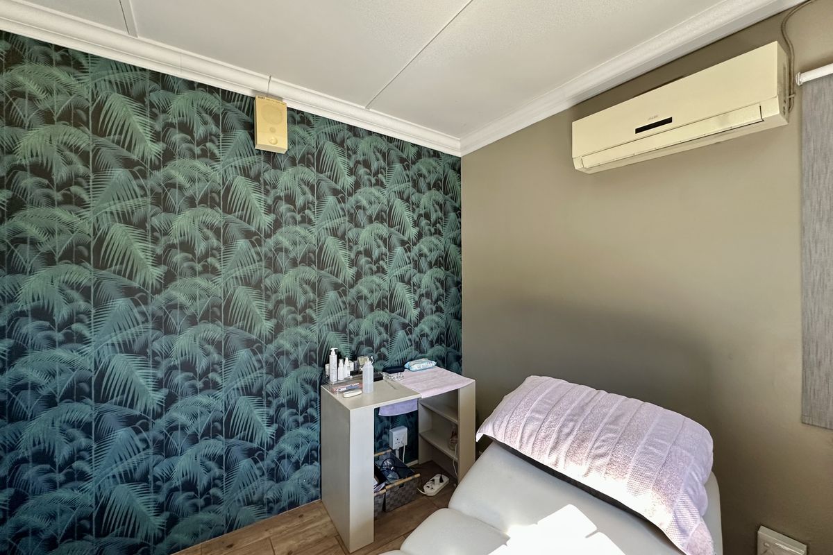 A bedroom featuring patterned wallpaper, wood-look flooring, and a wall-mounted air conditioning unit.