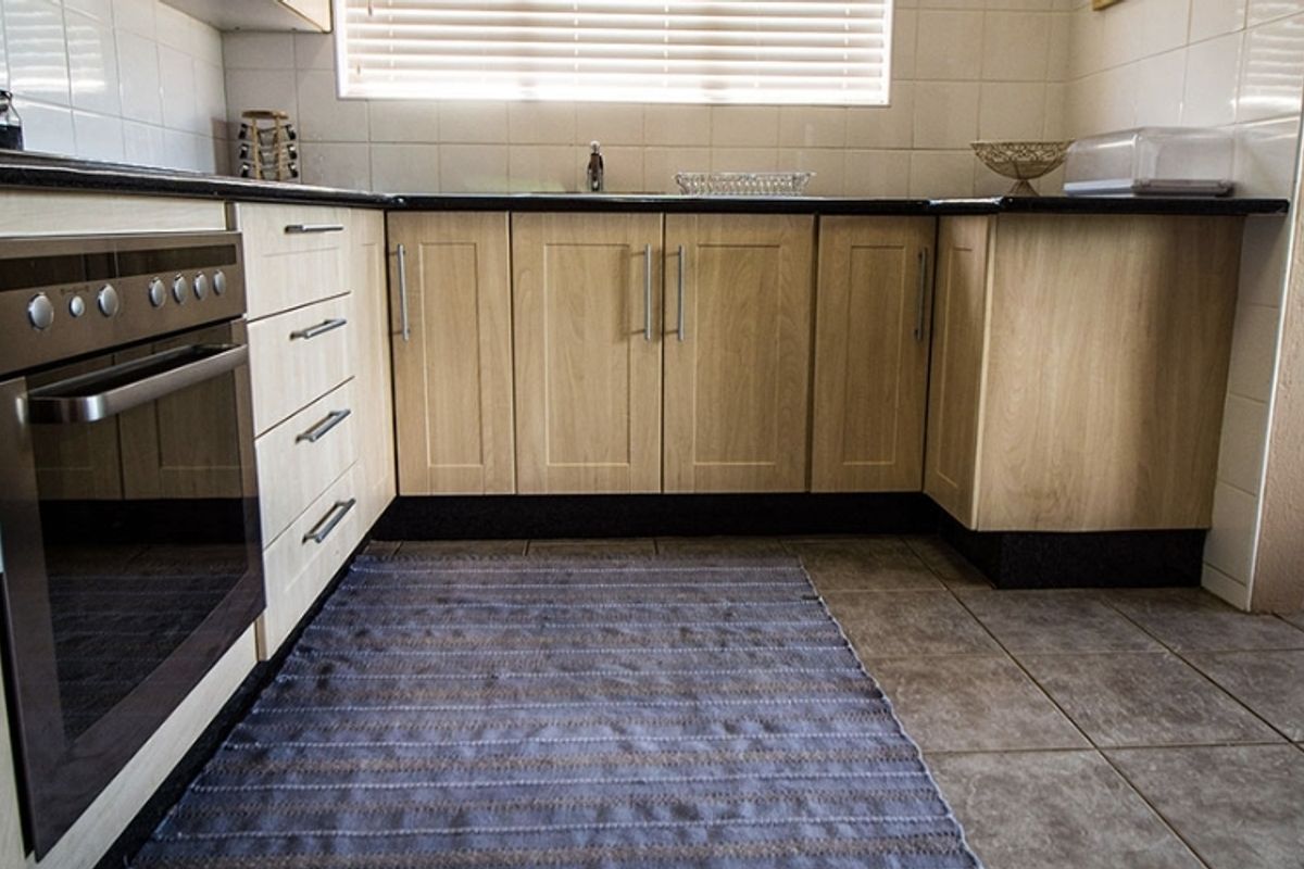 A functional kitchen featuring light wood-finish cabinetry, dark countertops, a built-in oven, and tiled flooring with a neutral backsplash.
