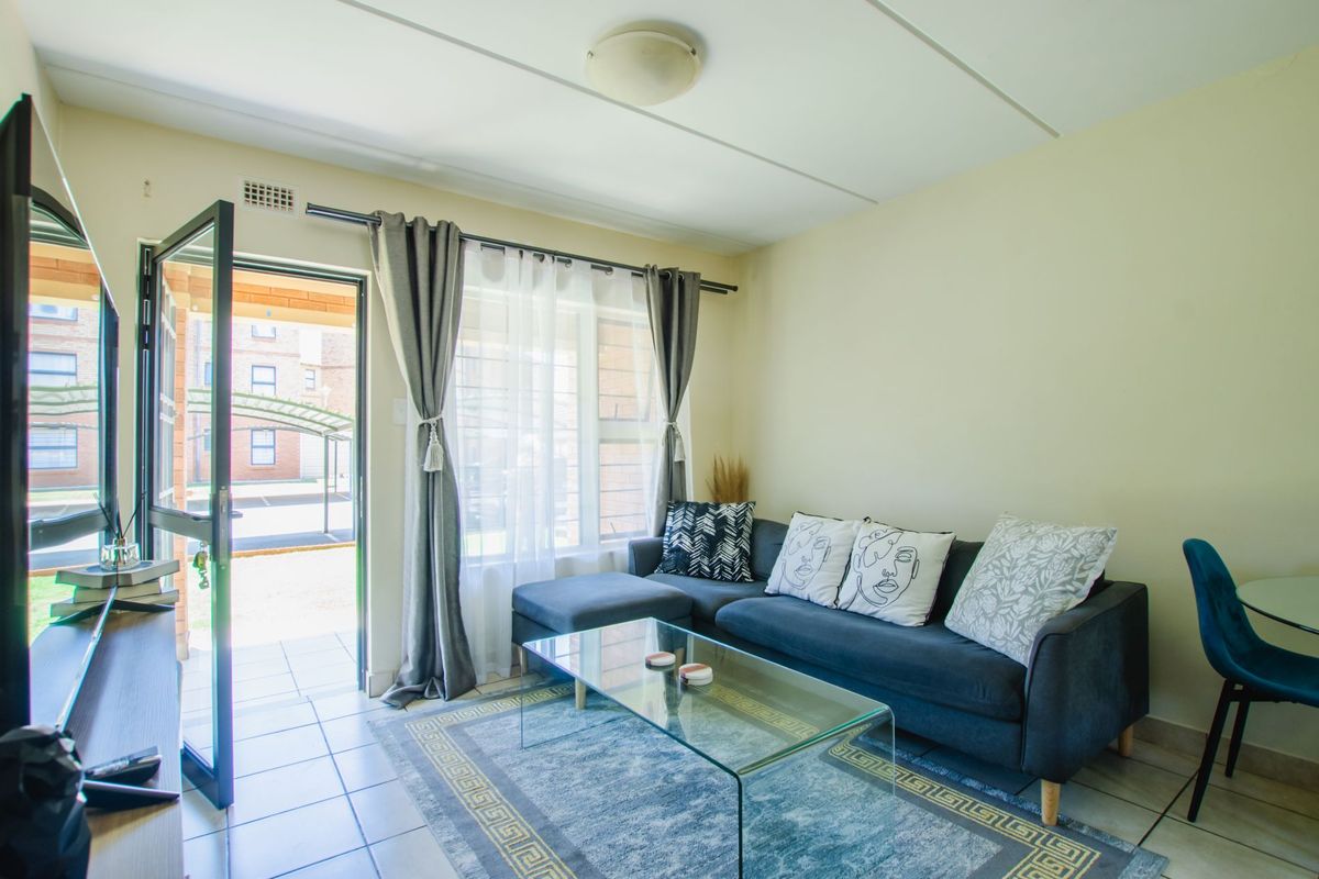 A bright living room featuring tiled flooring, a ceiling light fixture, and a sliding glass door providing direct access to the exterior.