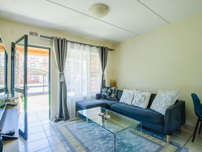 A bright living room featuring tiled flooring, a ceiling light fixture, and a sliding glass door providing direct access to the exterior.