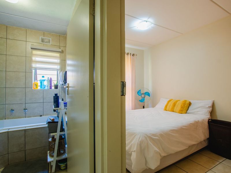 A view through a doorway showing a bedroom adjacent to a tiled bathroom with a built-in bathtub.