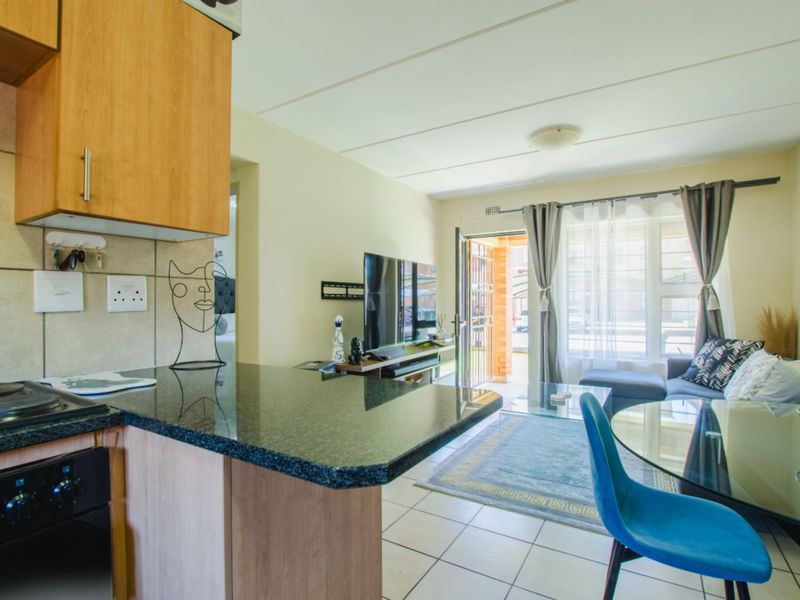 Open-plan living area featuring a functional kitchen with granite countertops and tiled flooring, leading directly to an exterior entrance.