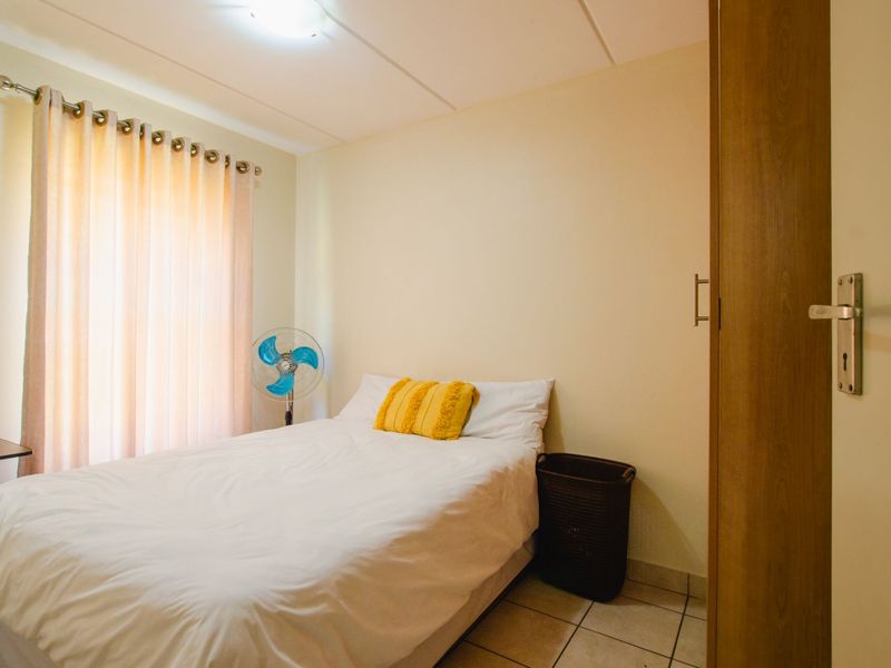 A functional bedroom featuring tiled flooring and a built-in cupboard, offering a simple and practical living space.