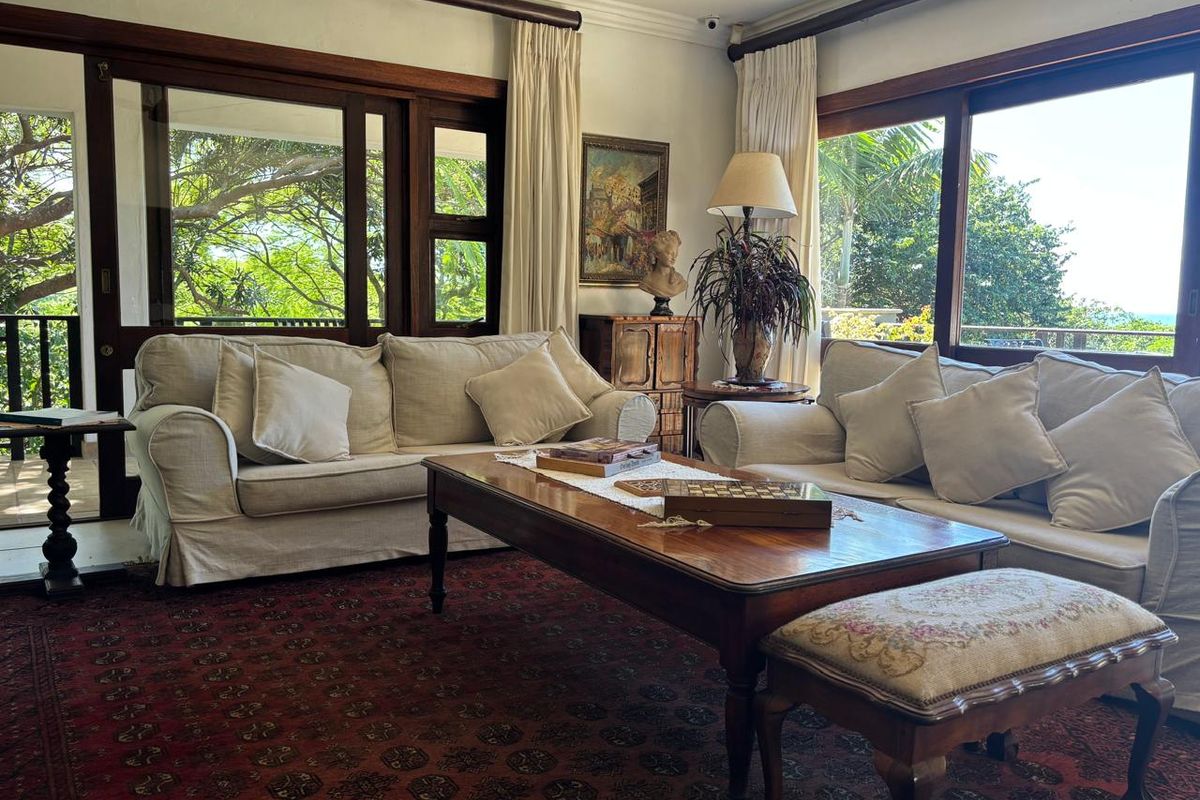 A bright living room featuring large wooden-framed sliding doors that provide ample natural light and views of the surrounding greenery.