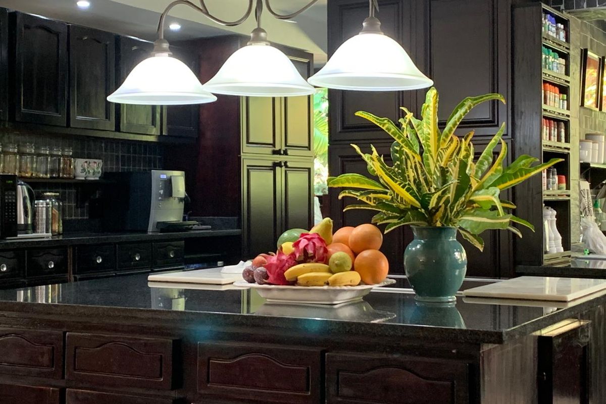 A well-appointed kitchen featuring dark wood cabinetry, a large central island with a granite countertop, and integrated lighting fixtures.