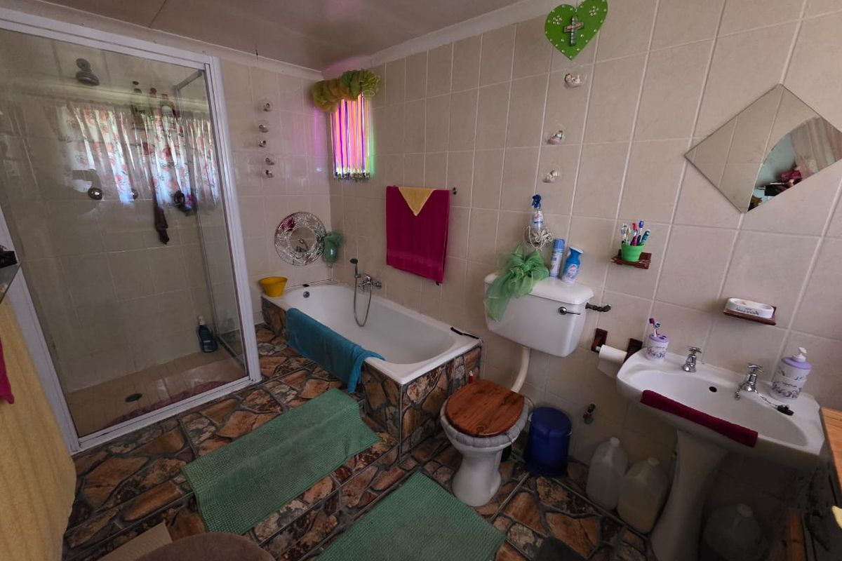 A dated bathroom featuring a separate shower enclosure, bathtub, pedestal basin, and toilet with tiled walls and stone-effect flooring.