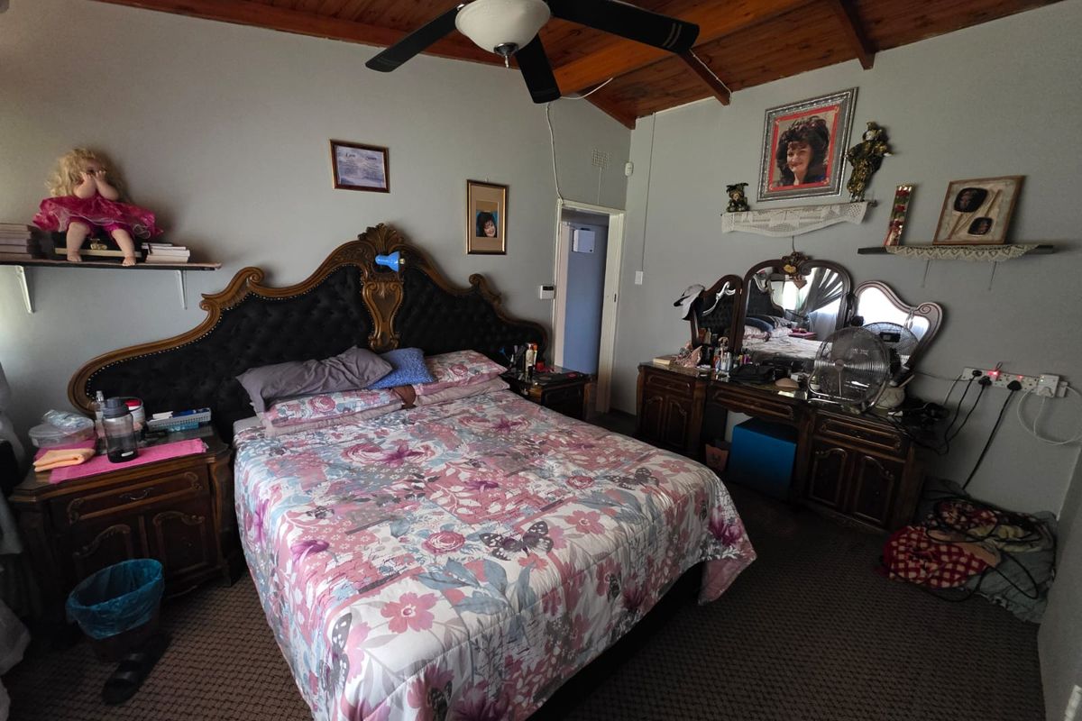 Spacious bedroom featuring a vaulted timber-paneled ceiling, ceiling fan, and carpeted flooring, offering a comfortable and traditional living space.