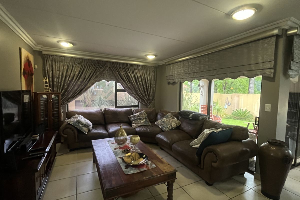 A spacious living room featuring tiled flooring, recessed ceiling lighting, and large sliding glass doors that provide access to the outdoor area.