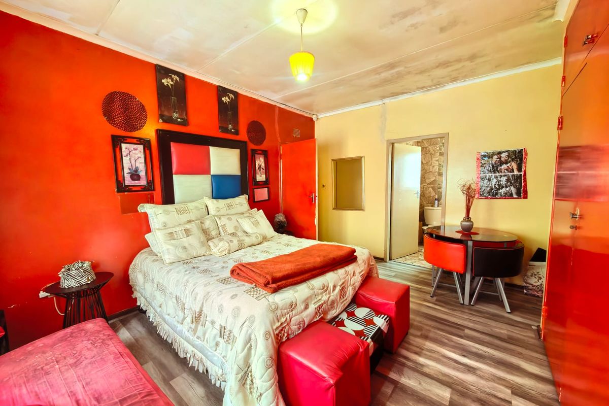 A bedroom featuring wood-look flooring, built-in cabinetry, and an en-suite bathroom access point.