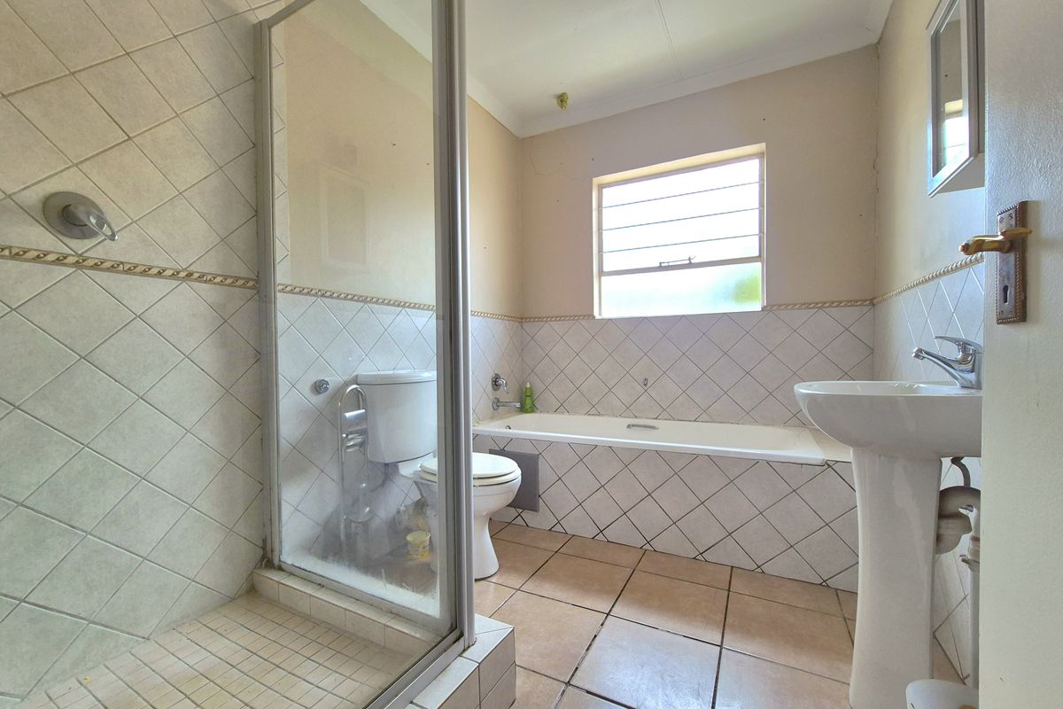 A functional bathroom featuring a separate shower enclosure, a built-in bathtub, a pedestal basin, and tiled flooring with wall-tiled accents.