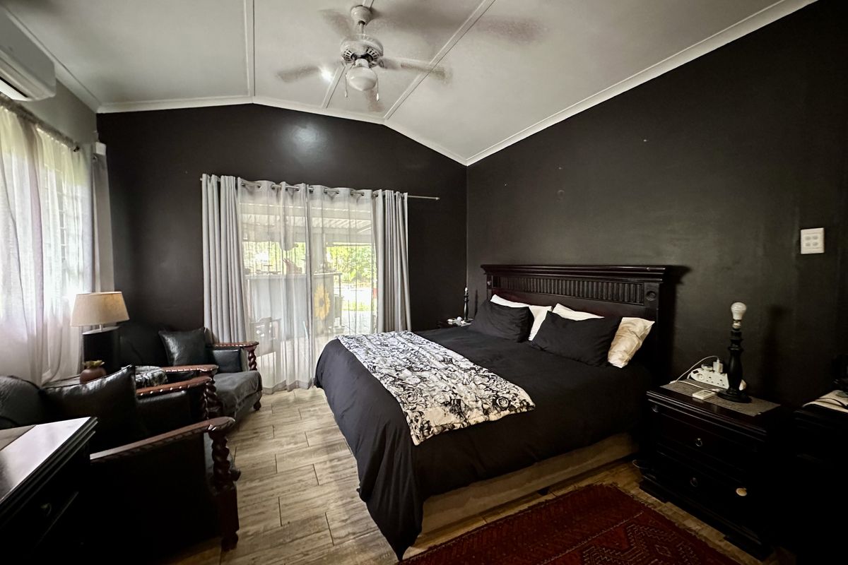 Spacious bedroom featuring tiled flooring, a vaulted ceiling with a central fan, and direct access to an outdoor patio area.