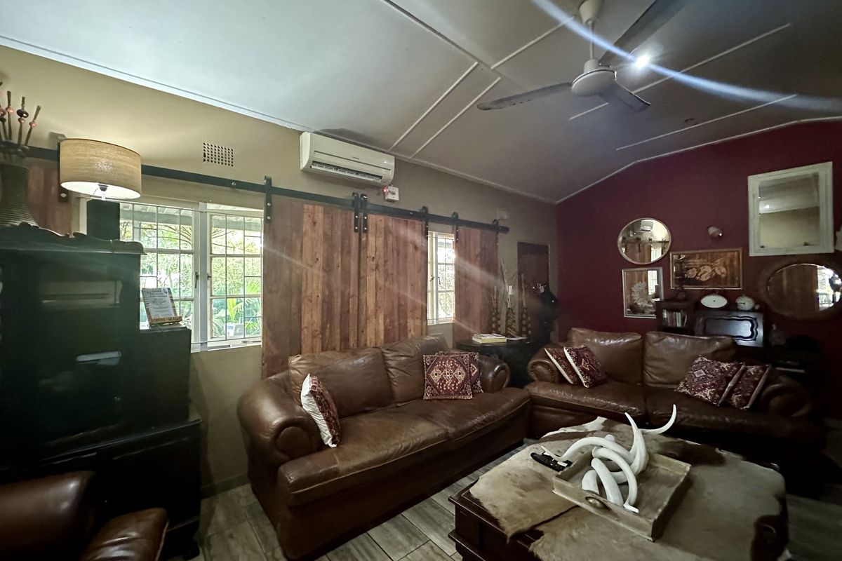 A cozy living room featuring a vaulted ceiling with a fan, split-system air conditioning, and rustic sliding barn-style window shutters.