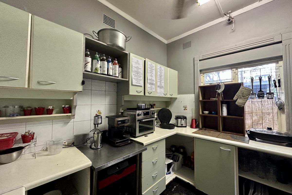 A functional kitchen area featuring dated cabinetry, tiled splashbacks, and stainless steel prep surfaces, suitable for renovation or modernization.