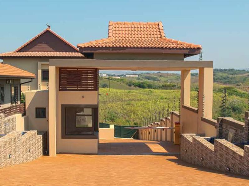 A well-maintained security entrance gatehouse for the townhouse complex, featuring stone cladding, tiled roofing, and integrated electric fencing.