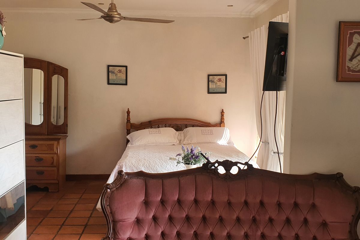 A bedroom featuring terracotta floor tiles and a ceiling fan, offering a warm and traditional aesthetic.