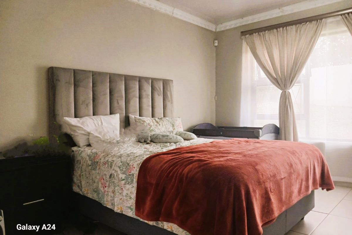 A well-maintained bedroom featuring neutral wall tones, decorative crown molding, and tiled flooring, providing a comfortable and functional living space.