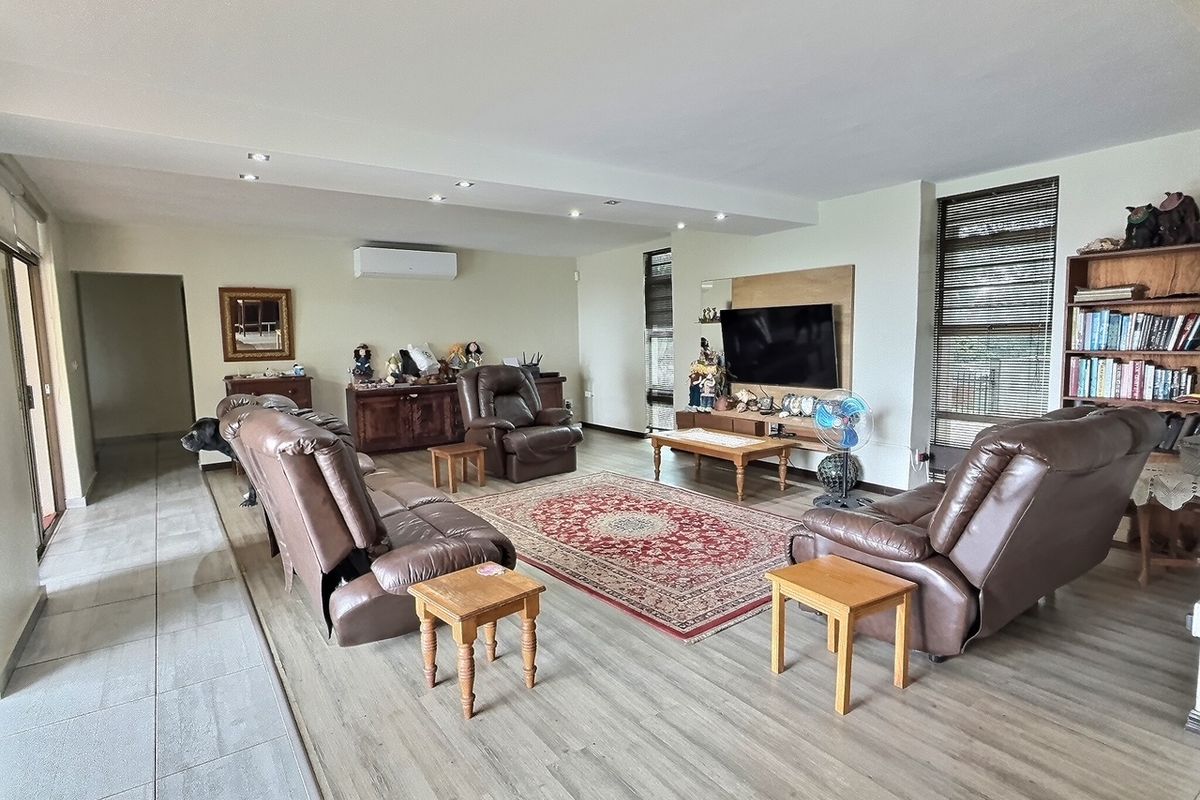 Spacious living room featuring light wood-look flooring, recessed ceiling lighting, and a wall-mounted air conditioning unit.