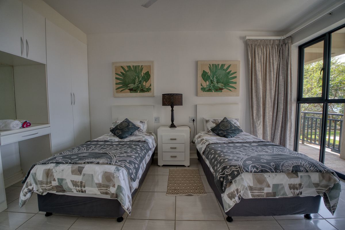 A well-maintained bedroom featuring built-in cupboards, tiled flooring, and a sliding glass door providing access to an outdoor balcony area.