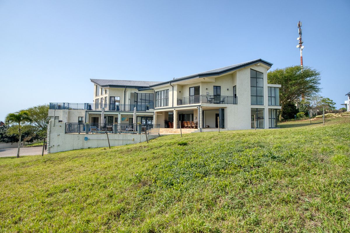 A spacious multi-level residential property featuring a modern stucco facade, expansive balconies, and large windows overlooking a landscaped rear garden area.