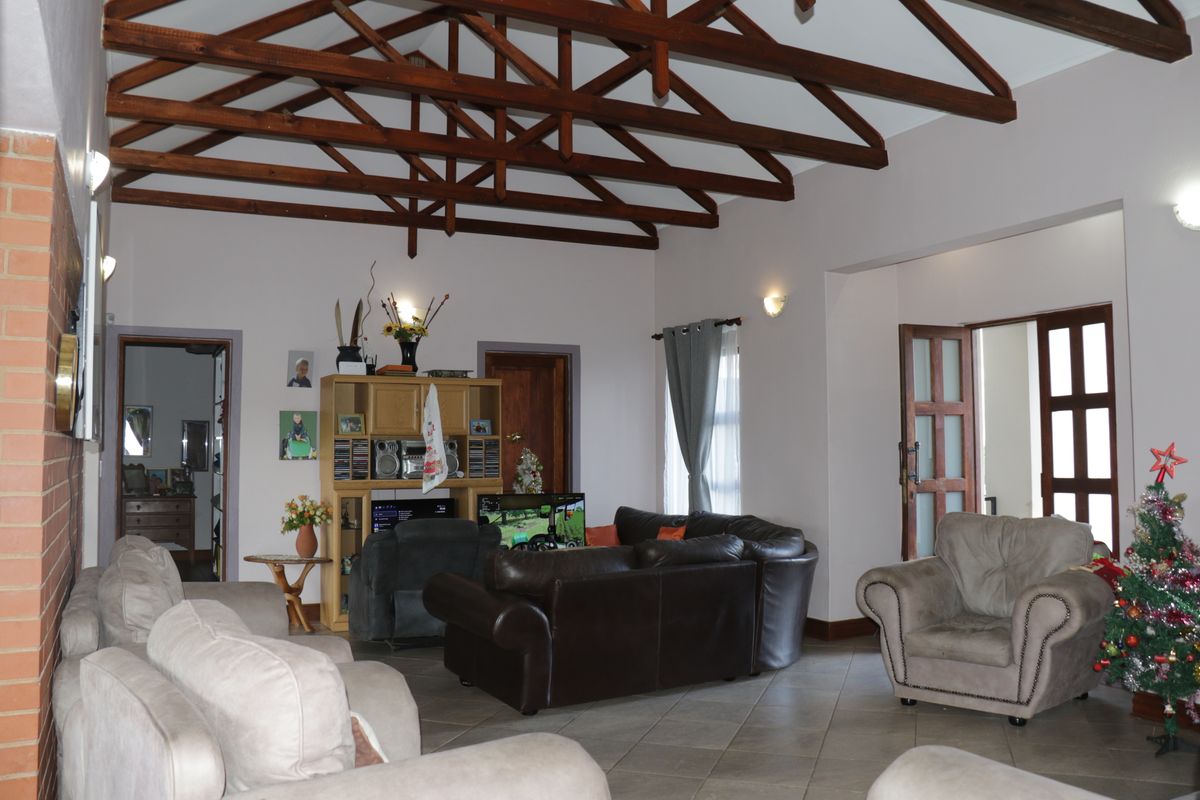 Spacious living room featuring high vaulted ceilings with exposed timber trusses and tiled flooring, providing an open and airy atmosphere.
