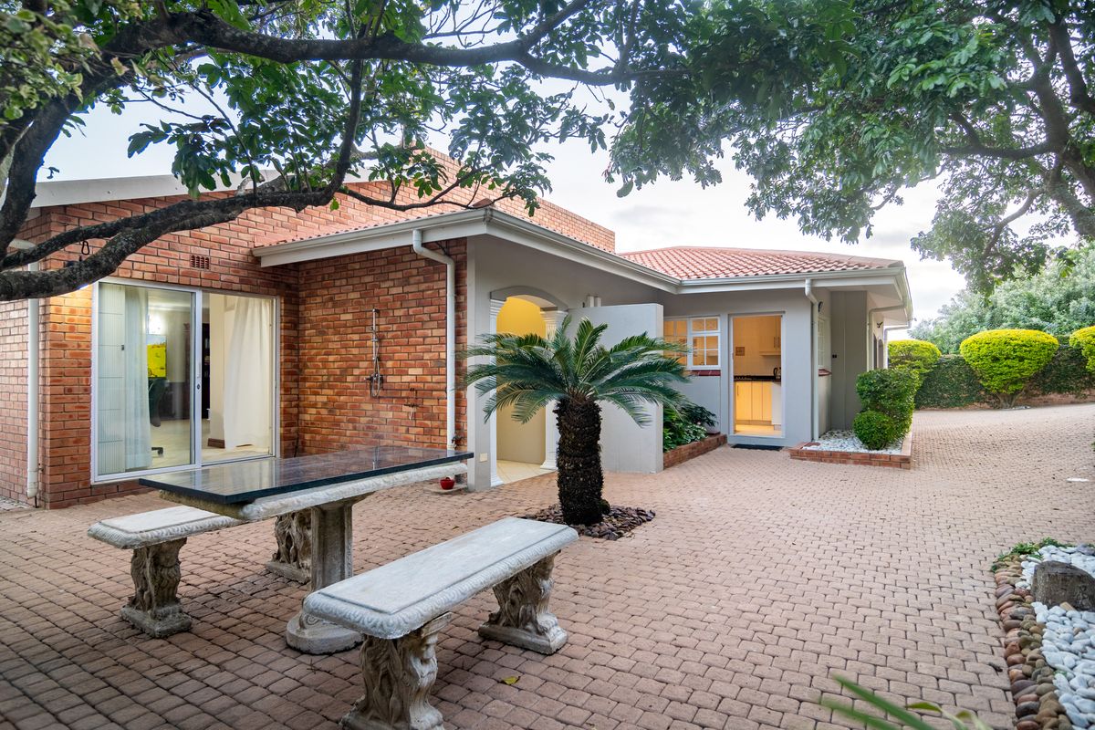 A well-maintained rear courtyard featuring brick exterior walls, paved flooring, and direct access to the home through sliding glass doors.