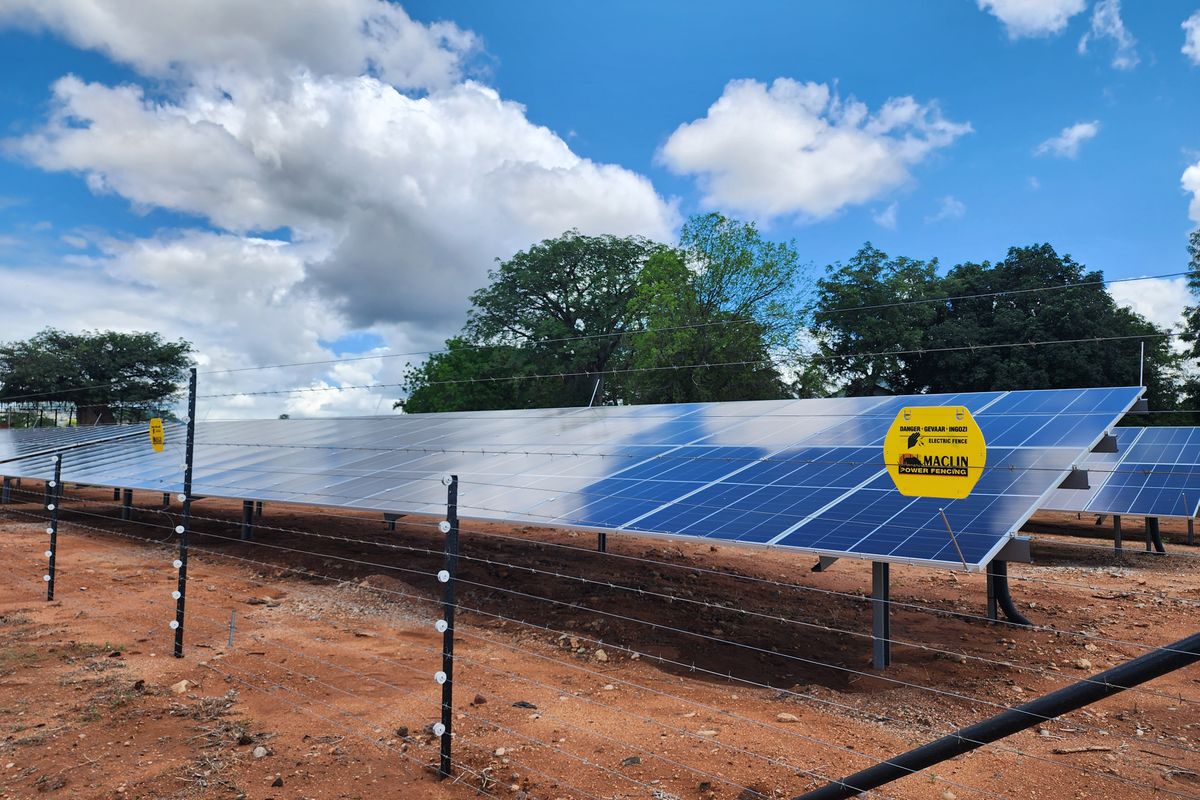 Ground-mounted solar panel array secured within an electric perimeter fence on the farm property.